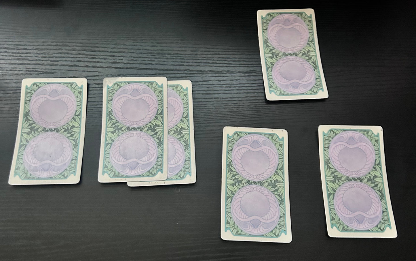 A spread of five tarot cards laid out on a dark surface, with designs visible on the cards.