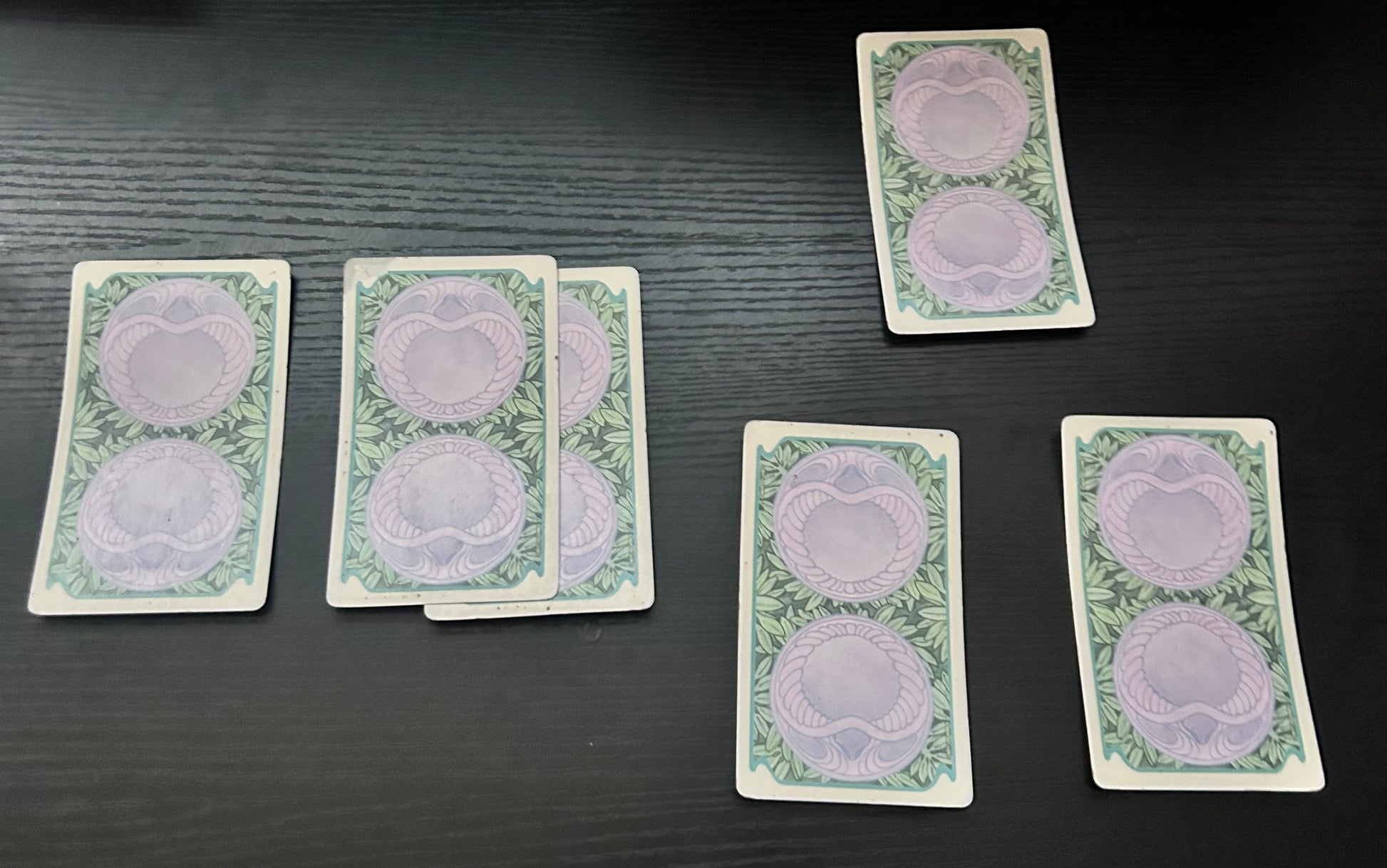 A spread of five tarot cards laid out on a dark surface, with designs visible on the cards.