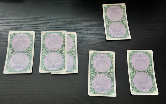 A spread of five tarot cards laid out on a dark surface, with designs visible on the cards.